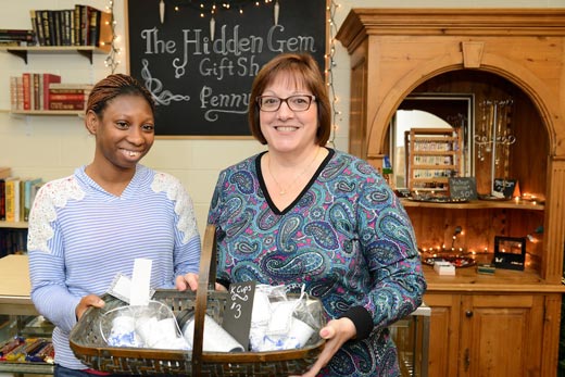 Young woman and staff person holding a basket of gifts at Hidden Gem Gift Store 